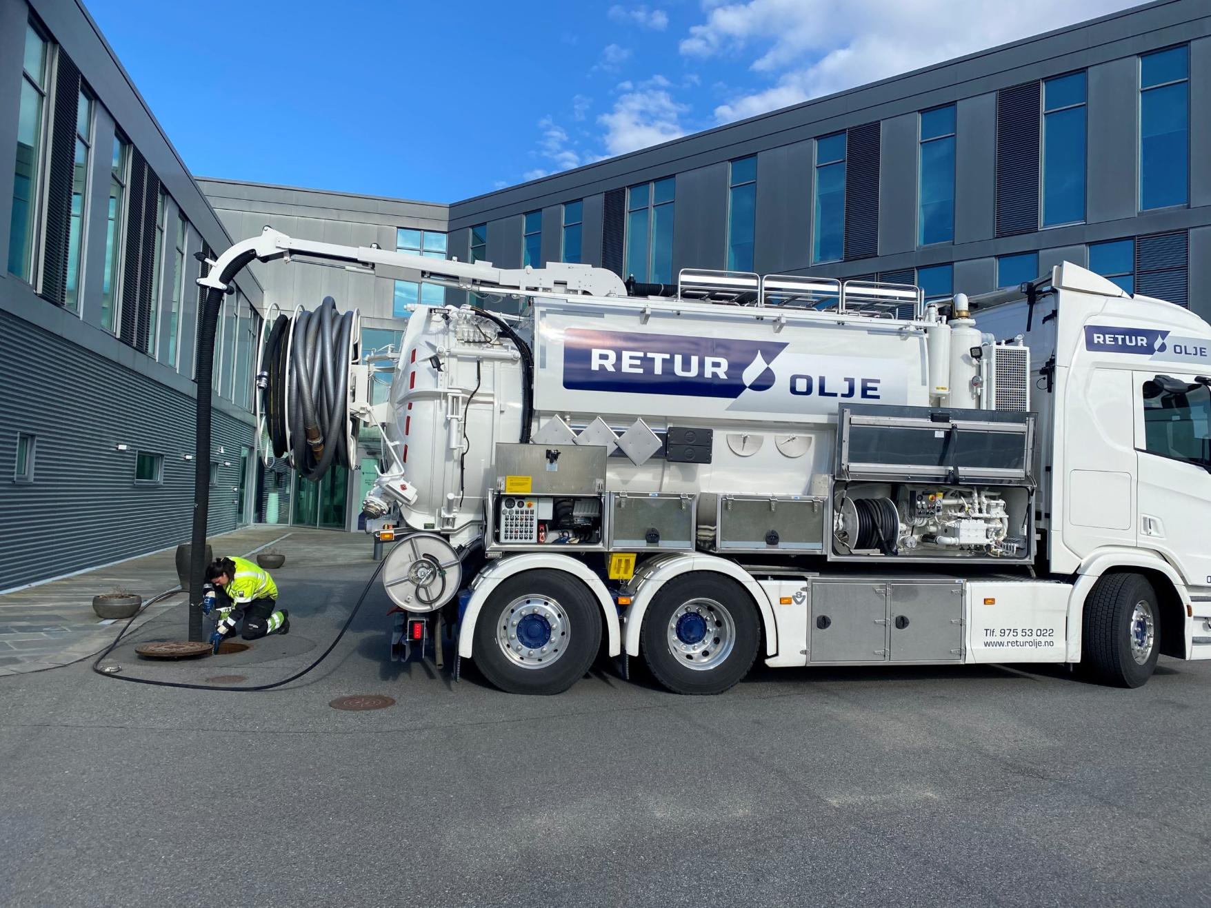 Hvit tankbil med slanger